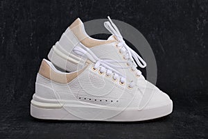 Light womens leather sneakers on a dark background close up