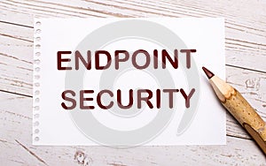 On a light wooden background, a colored pencil and a white sheet of paper with the text ENDPOINT SECURITY