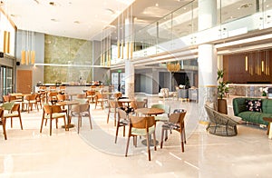 Light wooden and marble tile floor interior of modern cafe with double ceiling height. Lobby bar in hotel hall with split level photo