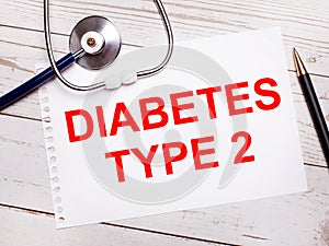 On a light wooden table there is a stethoscope, a pen and a sheet of paper with the text DIABETES TYPE 2. Medical concept