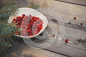 A light wooden table top with a plate of freshly baked muffins decorated with red berries sprinkled with white powder and a plate