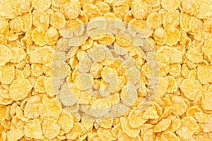 Light yellow corn flakes texture as a background. Top view cereal box for morning breakfast close up.