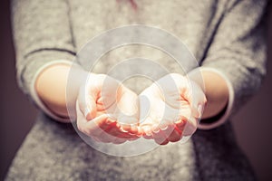 Light in young woman's hands. Sharing, giving, offering, taking care, protection.