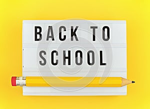 Lightbox with BACK TO SCHOOL text and big funny pen on yellow background