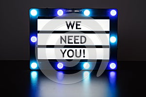 Lightbox with blue lights in dark room with words - we need you