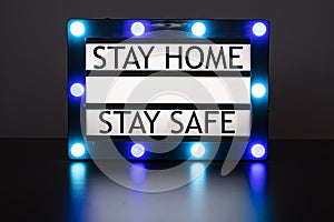 Lightbox with green and blue lights in dark room with words stay home, stay safe