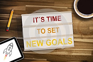 Lightbox or light box with business message Time to set new goals on a wooden table with coffee, pencil and tablet