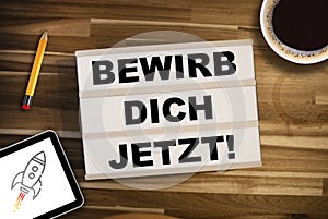 Lightbox or light box with the german words for Join our team - bewirb dich jetzt on a wooden table