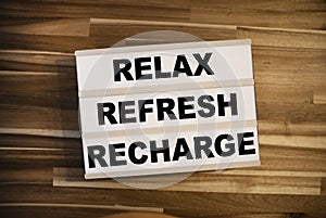 Lightbox or light box with message Reflex Refresh Recharge on a wooden table