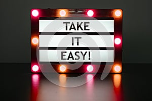 Lightbox with red lights in dark room with phrase- take it easy