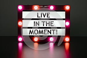 Lightbox with red and orange lights in dark room with words - living in the moment