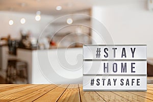 Lightbox sign with text hashtag #STAY HOME and #STAY SAFE blurred coffee shop background. COVID-19. Stay home save concept