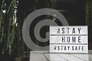 Lightbox sign with text hashtag #STAY HOME and #STAY SAFE on white table. COVID-19. Stay home save concept