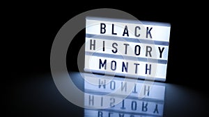 Lightbox with text BLACK HISTORY MONTH on dark black background with mirror reflection. Message historical event