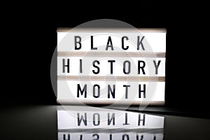 Lightbox with text BLACK HISTORY MONTH on dark black background with mirror reflection. Message historical event