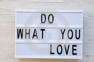 Lightbox with text `Do what you love` over white wooden surface, top view. From above, flat lay,