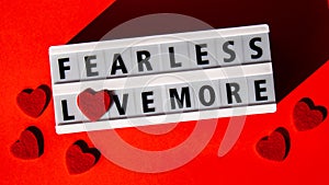 Lightbox with text FEAR LESS LOVE MORE. Motivational Words Quotes Concept with red hearts. Colorful red background