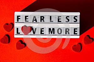 Lightbox with text FEAR LESS LOVE MORE. Motivational Words Quotes Concept with red hearts. Colorful red background