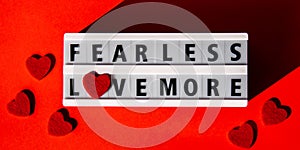 Lightbox with text FEAR LESS LOVE MORE. Motivational Words Quotes Concept with red hearts. Colorful red background