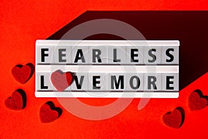 Lightbox with text FEAR LESS LOVE MORE. Motivational Words Quotes Concept with red hearts. Colorful red background