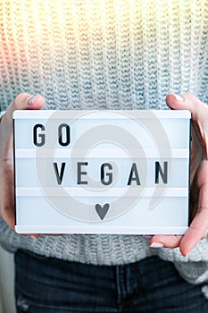 Lightbox with text GO VEGAN in female hands. Veganism, vegetarian healthy lifestyle.