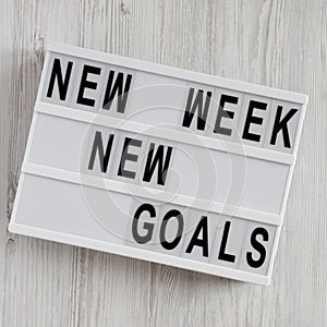 Lightbox with text `New week new goals` over white wooden surface, top view. From above, flat lay, overhead