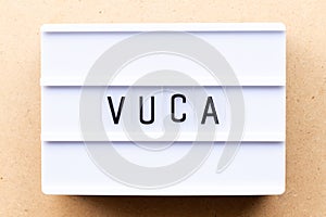 Lightbox with word VUCA abbreviation of Volatility, uncertainty, complexity and ambiguity on wood background