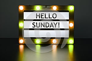 Lightbox with yellow and orange lights in dark room with words - Hello Sunday!banner, black background, bright, business, calendar