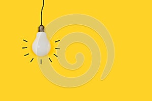 Lightbulb hanging on a yellow background with copy space