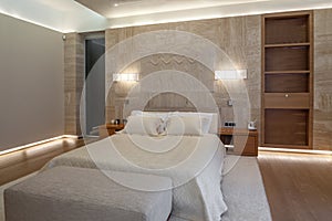 Lighted bedroom with marble wall and sculptural panel near double bed