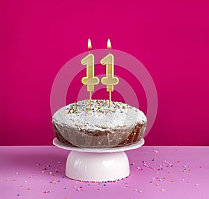 Lighted birthday candle number 11 - Birthday card on pink background