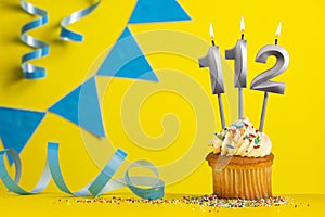 Lighted birthday candle number 112 - Yellow background with blue pennants