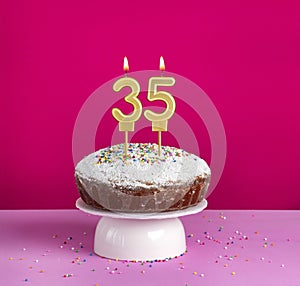 Lighted birthday candle number 35 - Birthday card on pink background