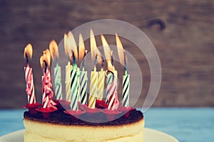 Lighted birthday candles on a cheesecake, with a retro effect photo