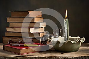 Lighted candle and old books