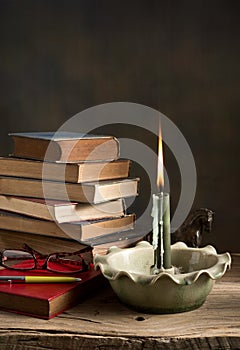 Lighted candle and old books