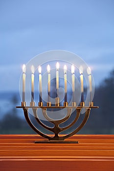 Lighted candles burning in traditional Jewish menorah for Jewish Hanukkah chanukkiah holiday with blue background