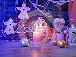 Lighted candles, decorative lights, balls, Christmas decor on a wooden table, wooden background