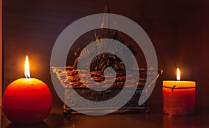 2 lighted candles with a wicker basket behind photo