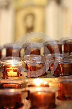 Lighted devotion candles in an orange glass jar photo