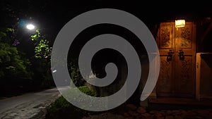 A lighted door in vintage style next to the road on a quiet night.Night panorama