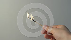 A lighted match burns with smoke on a gray background. Concept of slow-motion video with fire. The hand lights a match.