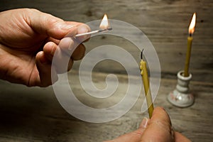 A lighted match in his hand and the candle
