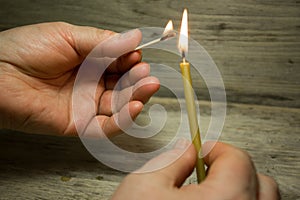 A lighted match in his hand and the candle