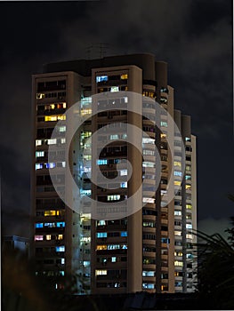 Lighted windows of homes of an HDB high-rise apartment block at night