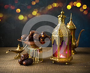 Lightened lantern and dates fruit on wooden table over dark background. Ramadan kareem holiday celebration concept