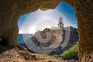 Lighthouse at Akrotiri through a frame of a window of a cave, Santorini.