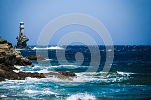 lighthouse in andros island greece in day light and sea waves