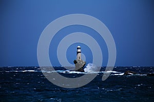 Lighthouse in andros island greece in day light and sea waves in a windy day