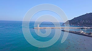 Lighthouse on background of seascape and coastal city. Clip. Top view of beautiful seascape with white lighthouse off
